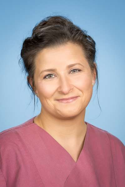 Eine Frau in einem weißen Laborkittel lächelt in die Kamera.