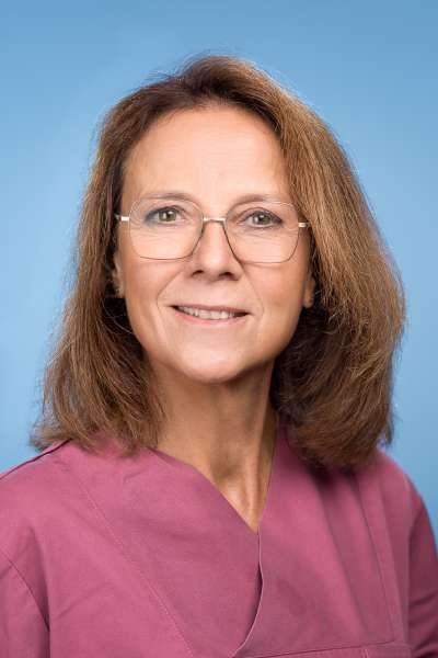 Eine Frau mit Brille und rosa Kasack lächelt in die Kamera.