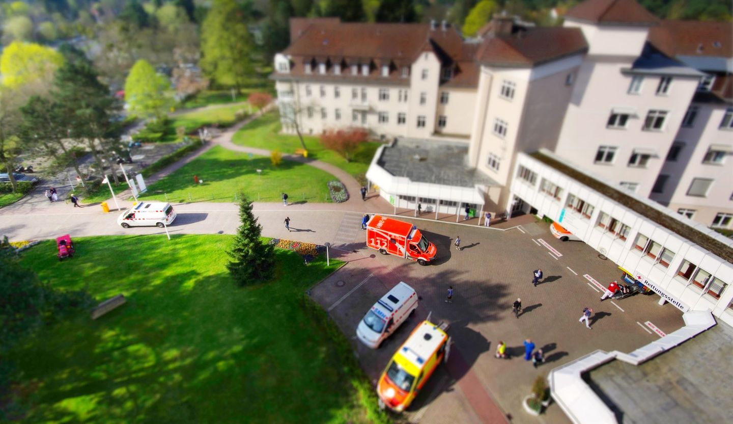 Eine Luftaufnahme eines Krankenhauses mit davor geparkten Krankenwagen.