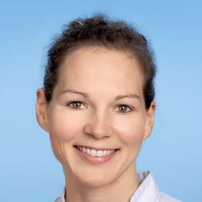 Eine Nahaufnahme des lächelnden Frauengesichts vor blauem Hintergrund.