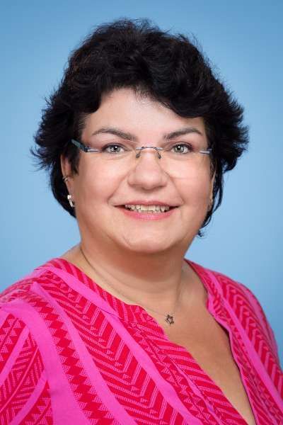 Eine Frau mit Brille und rosa Hemd lächelt in die Kamera.