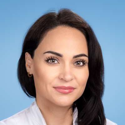 Eine Nahaufnahme des Gesichts einer Frau vor blauem Hintergrund.