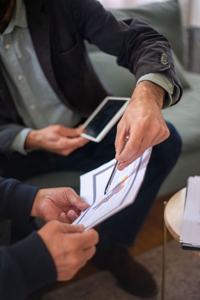 Due persone esaminano grafici stampati e uno smartphone in un ufficio informale