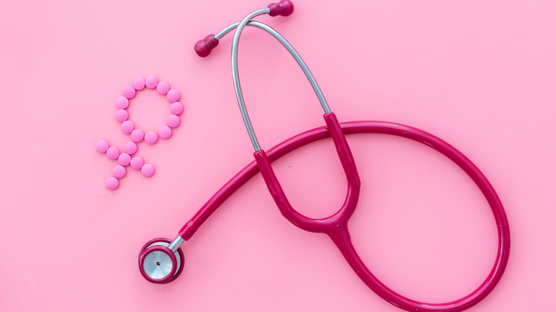 A pink stethoscope and pink pills on a pink background.