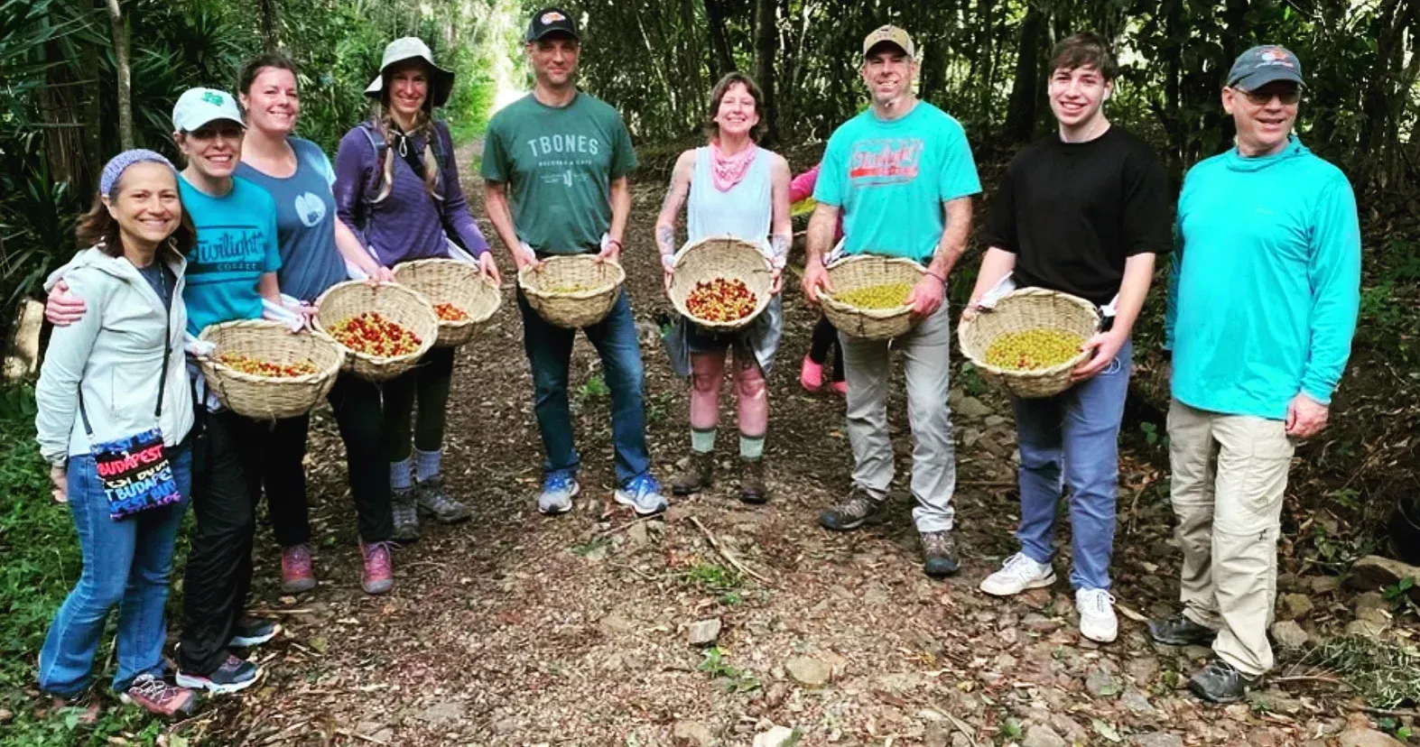 Group of people standing outdoors holding baskets of mushrooms in a wooded area