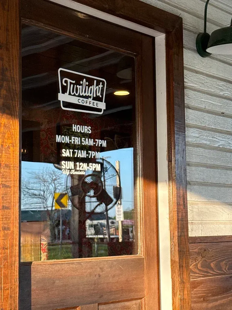 Glass door with Twilight hours sign reflecting a street scene outside the restaurant