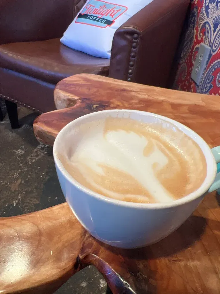 A blue cup of latte on a wooden table in a cozy café seating area.