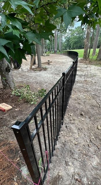 A black metal fence is surrounding a dirt path.