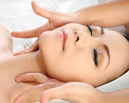A woman is getting a facial massage at a spa.
