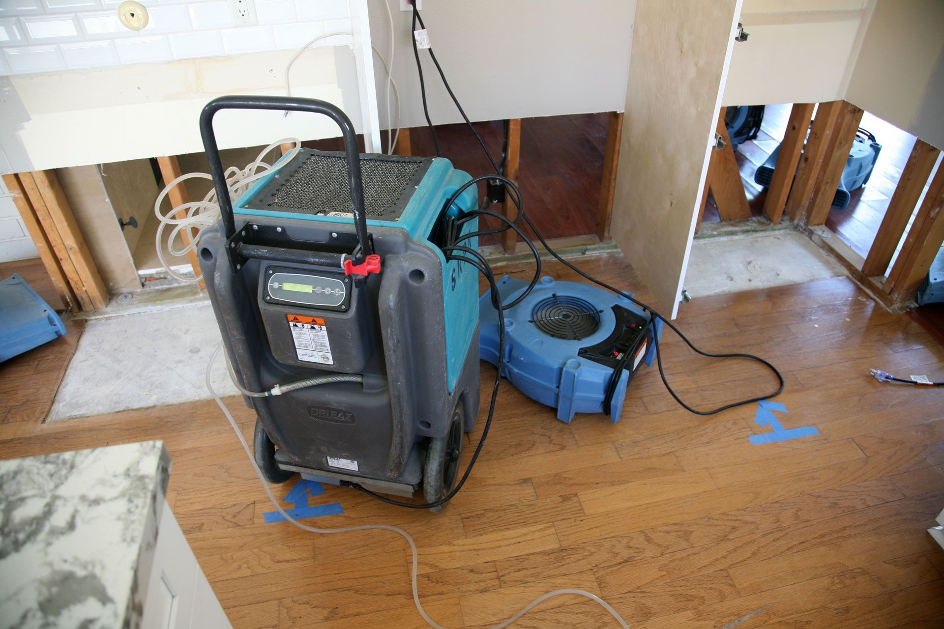 Vacuum and floor sander on a hardwood floor in a room under renovation
