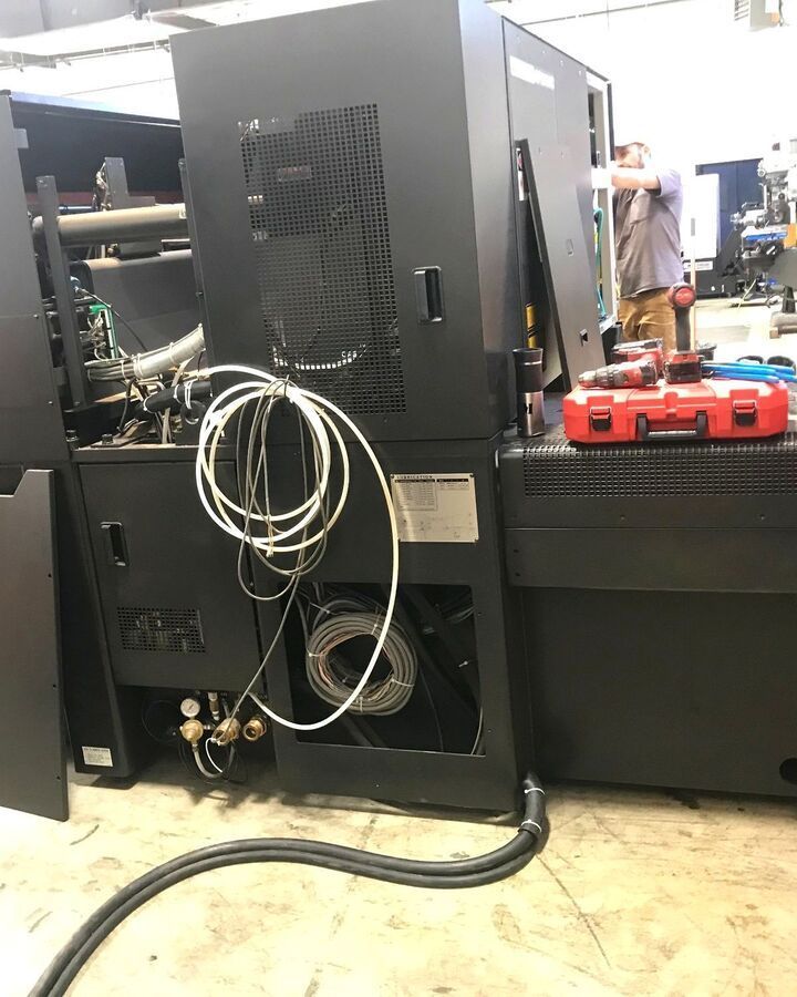 Industrial machine with cables and tools in a workshop, black equipment cabinet in the foreground.