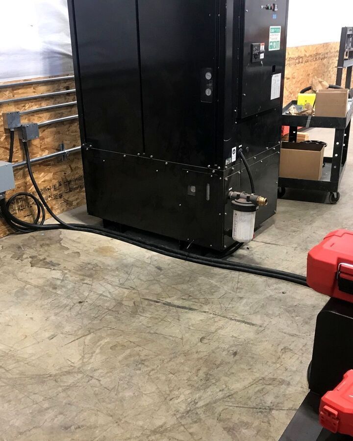 Industrial room with a large black cabinet, concrete floor, and red tool case in the foreground