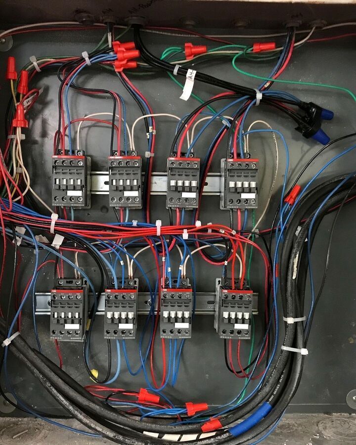 Electrical control panel with relays, wiring, and terminal blocks inside an open cabinet.