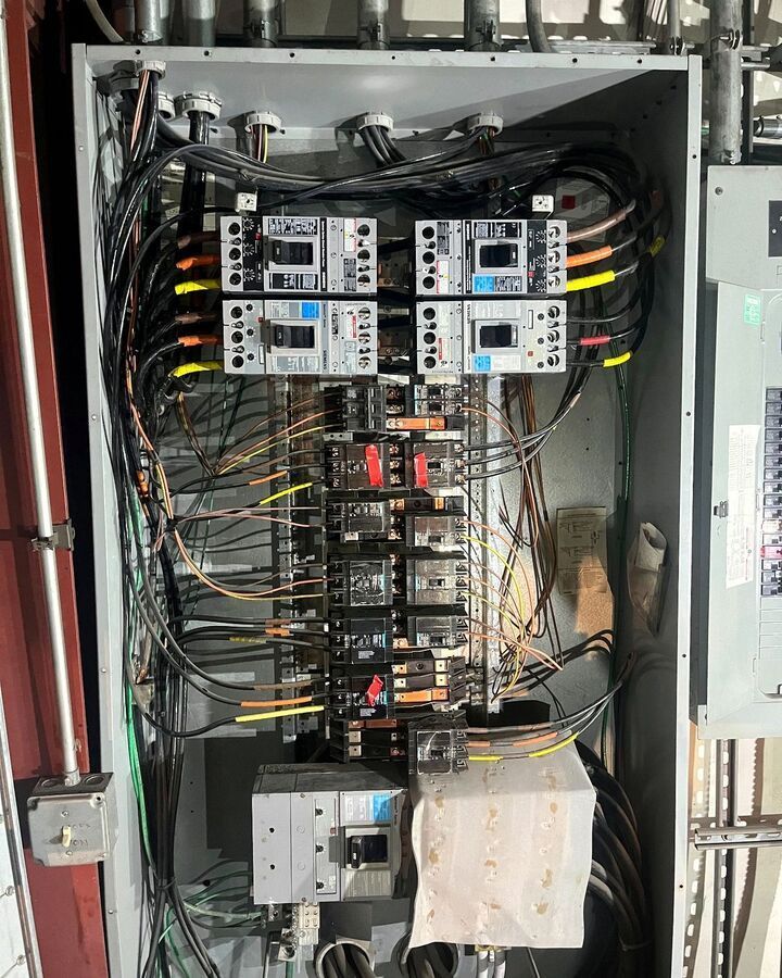 Electrical control cabinet with relays, wiring, and circuit breakers mounted inside.