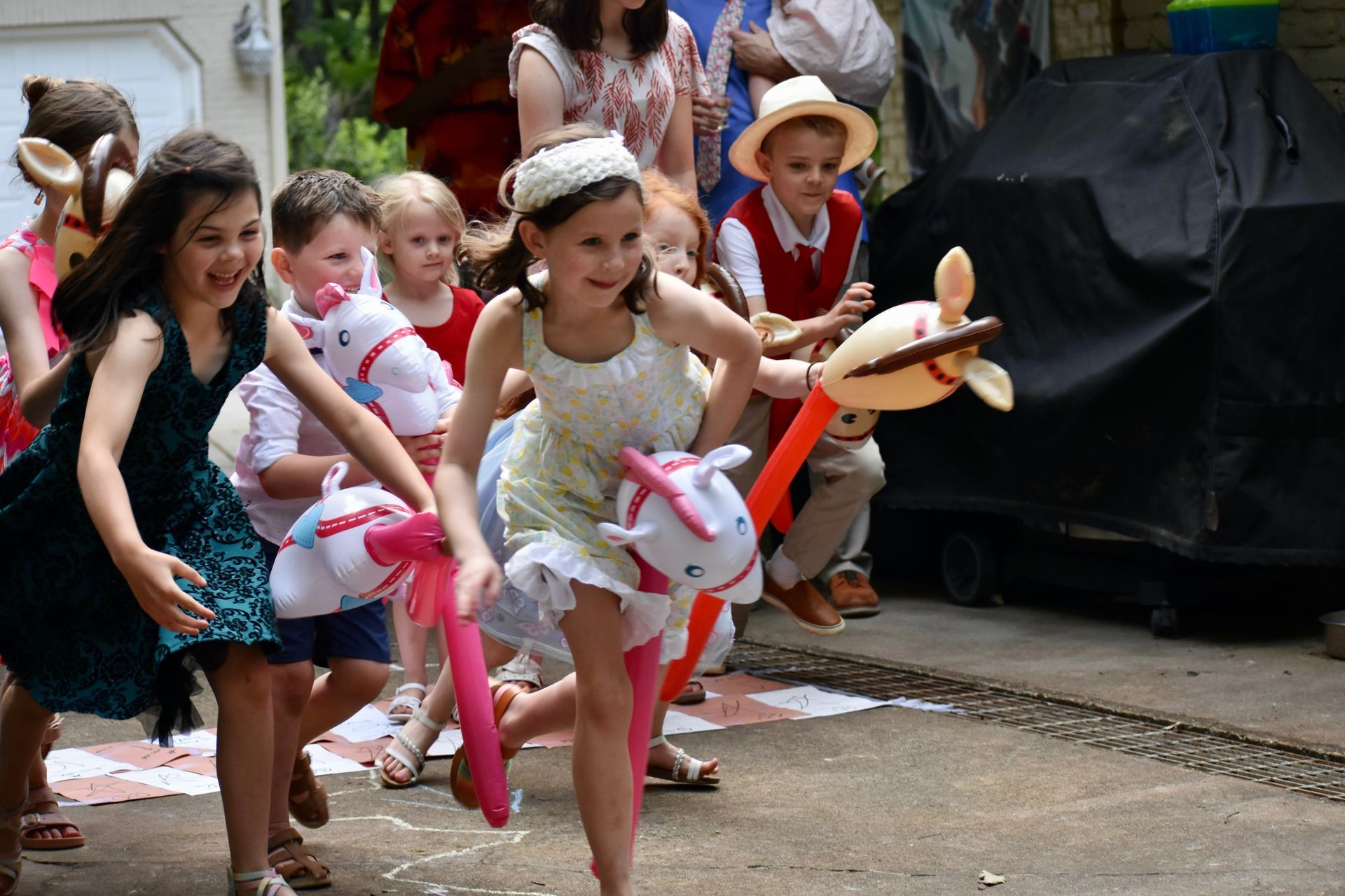 Children in festive costumes running in a street parade, carrying colorful props and streamers