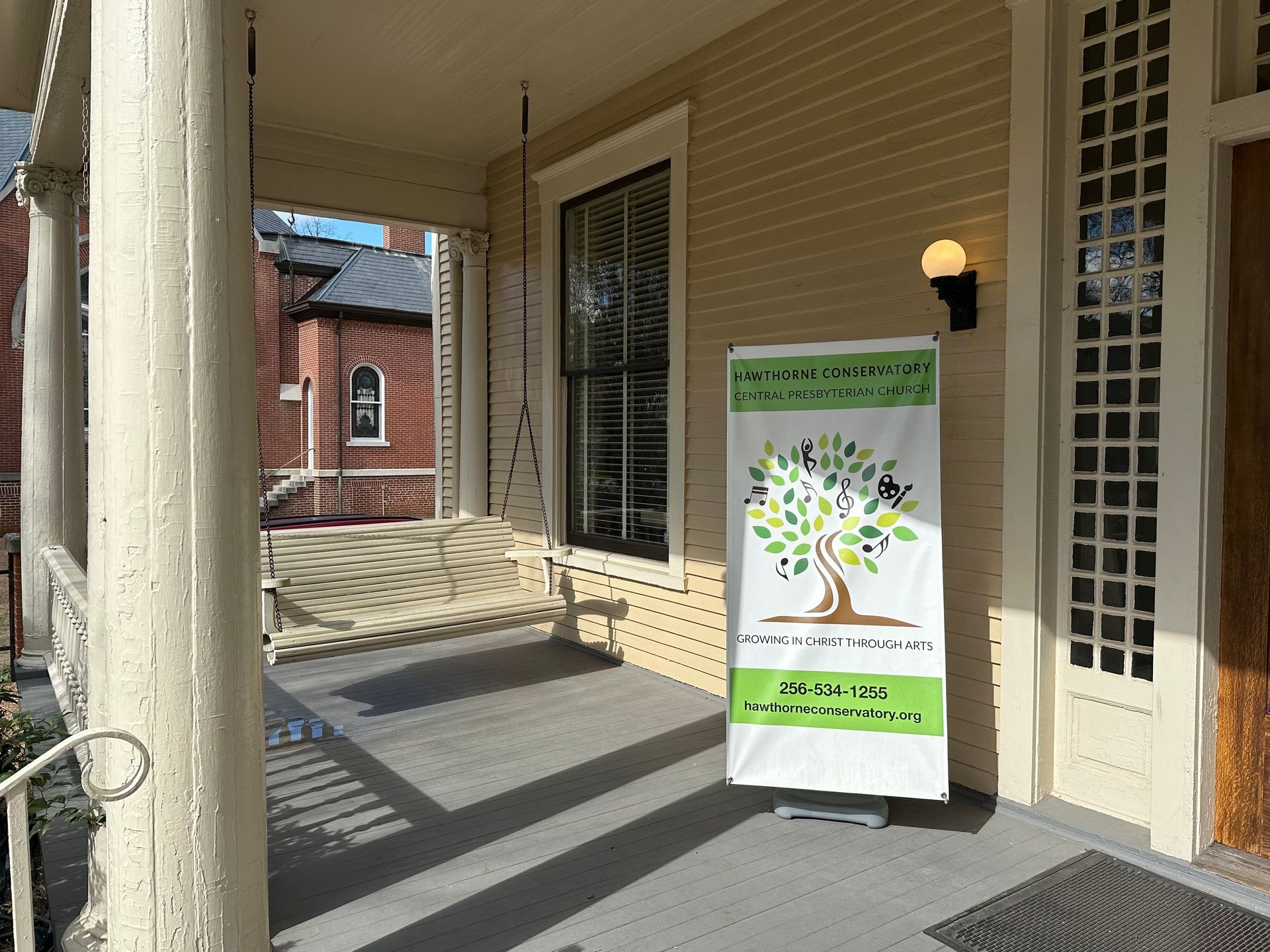 Covered walkway with a standing banner sign outside a building entrance in sunlight