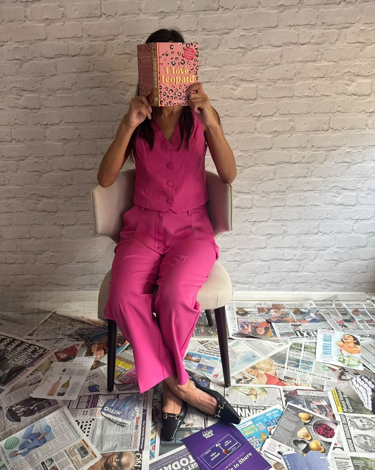Donna dressed in pink reading a book with newspaper on the floor to promote storytelling