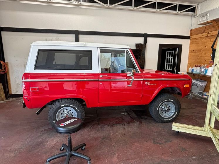 Red vintage SUV with white roof parked inside a garage