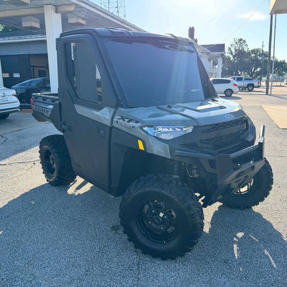 Black off-road utility vehicle parked on gravel in front of a building.