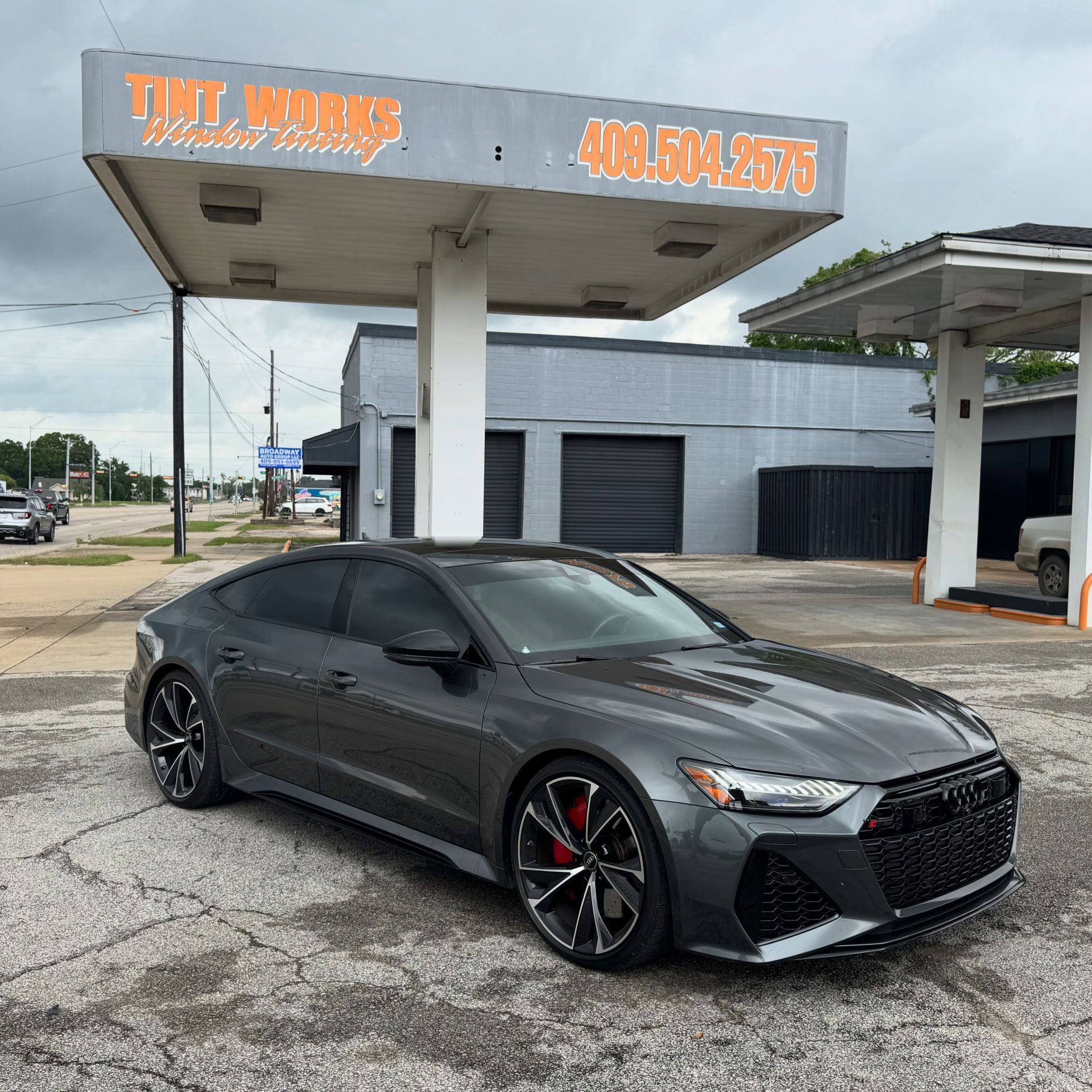 Black sedan parked at a car wash under a gray canopy.