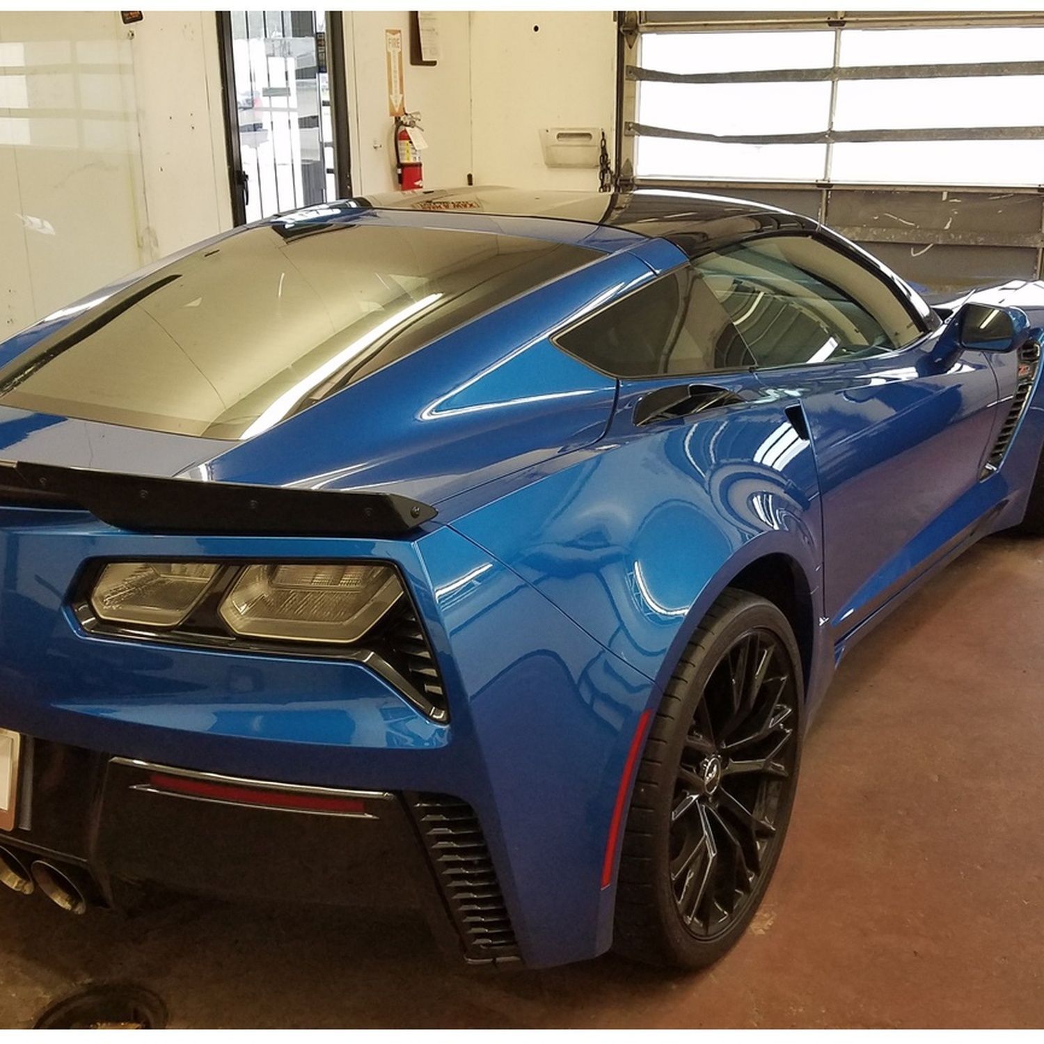 Blue sports car parked inside a garage, viewed from the rear-left side