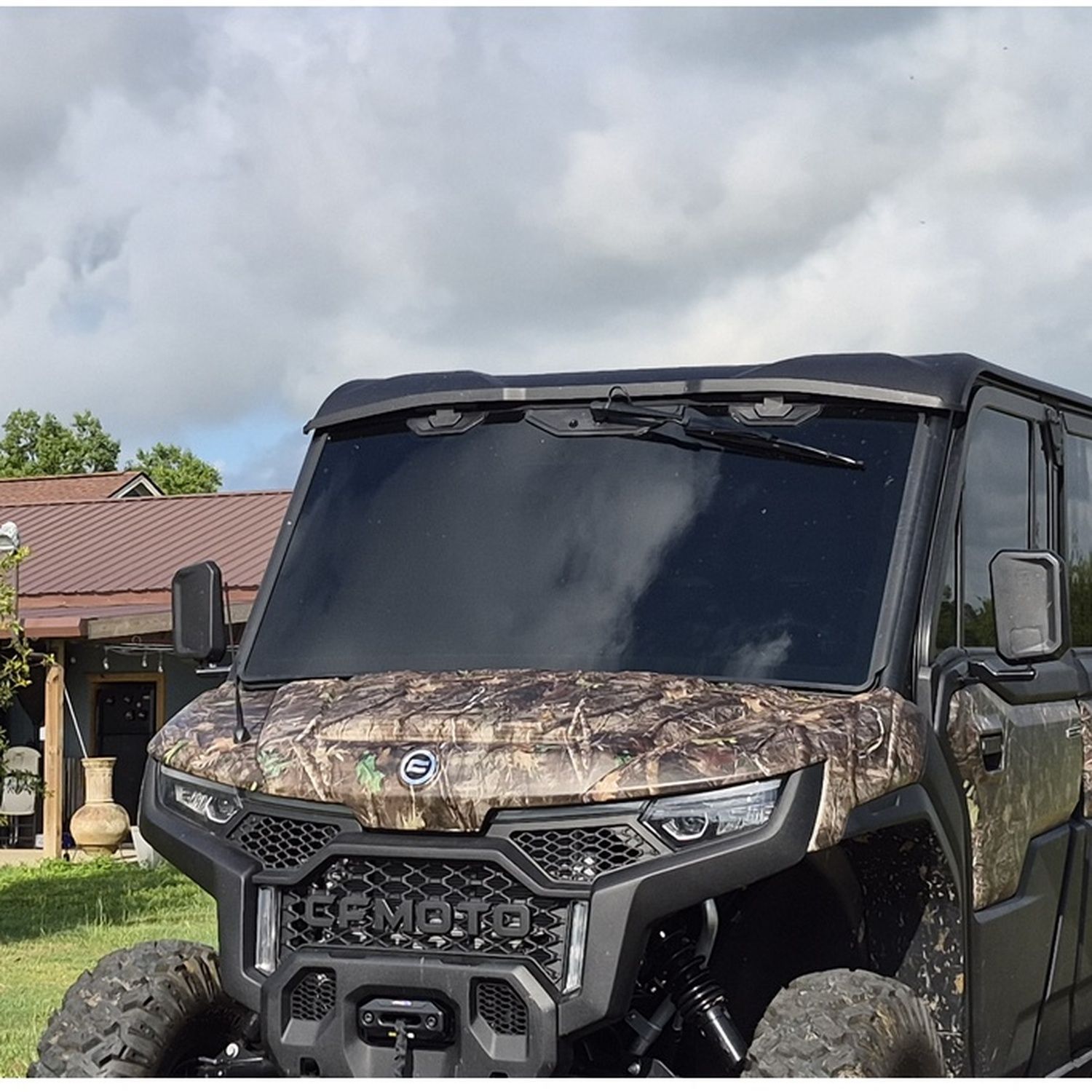Camouflaged off-road utility vehicle parked outdoors under cloudy sky