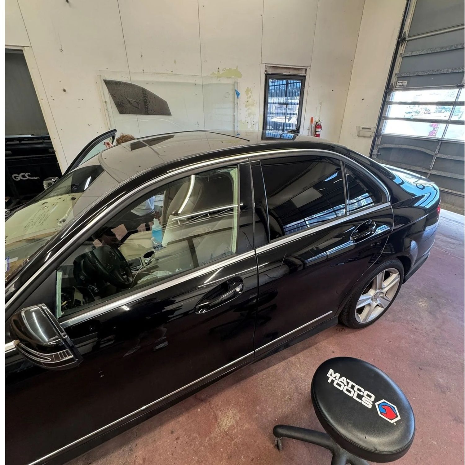 Black sedan parked inside an auto repair garage with the hood open.