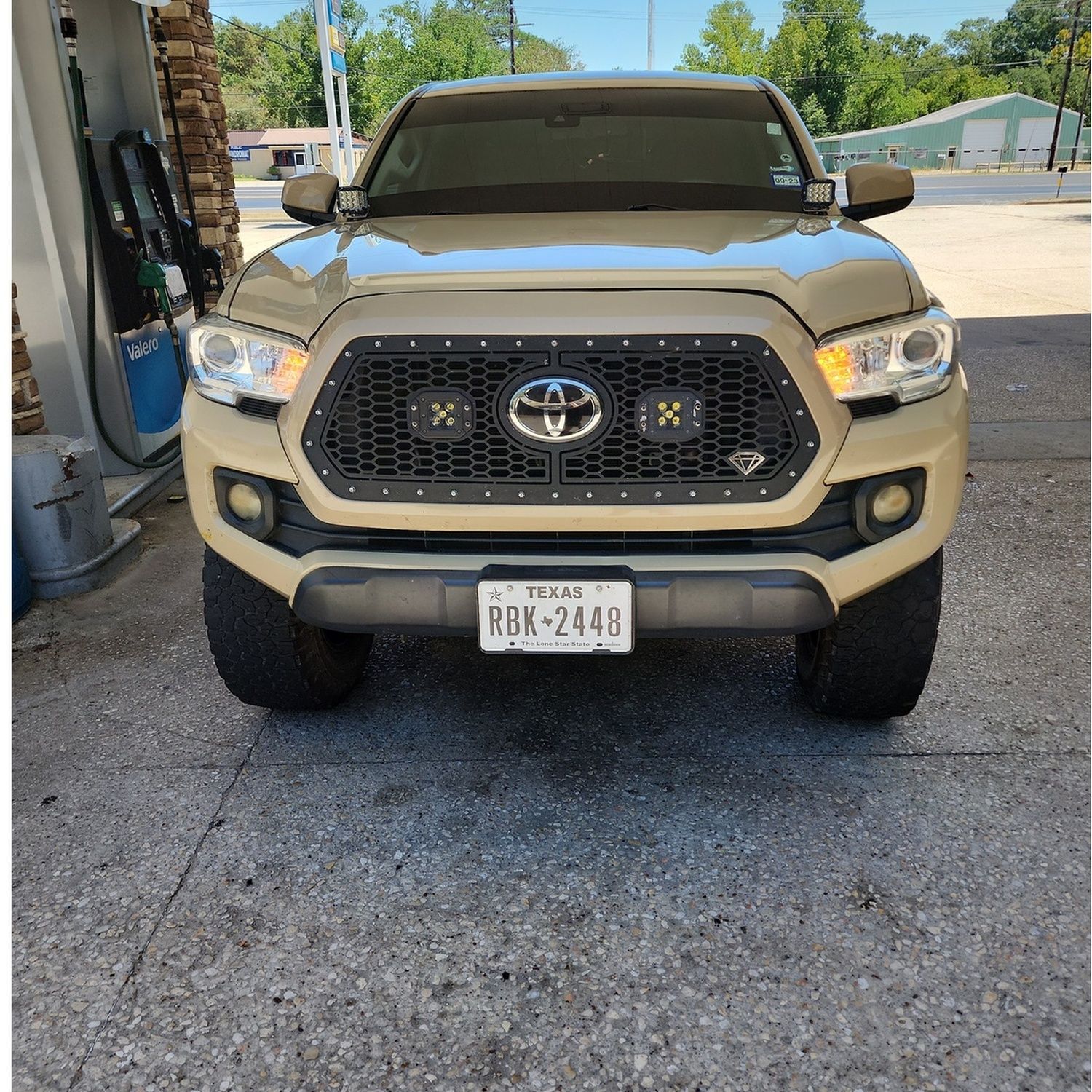 Beige Toyota Tacoma parked under a carport, front view.