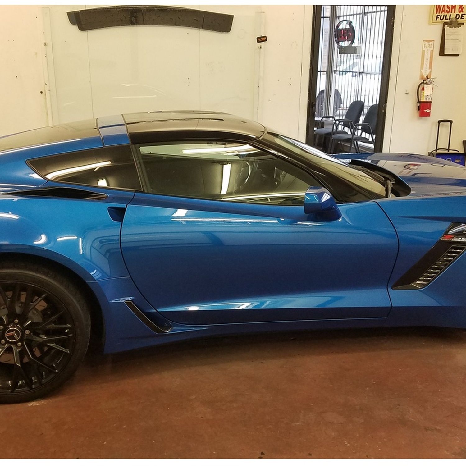 Blue sports car parked inside a garage, shown in side profile with black wheels.