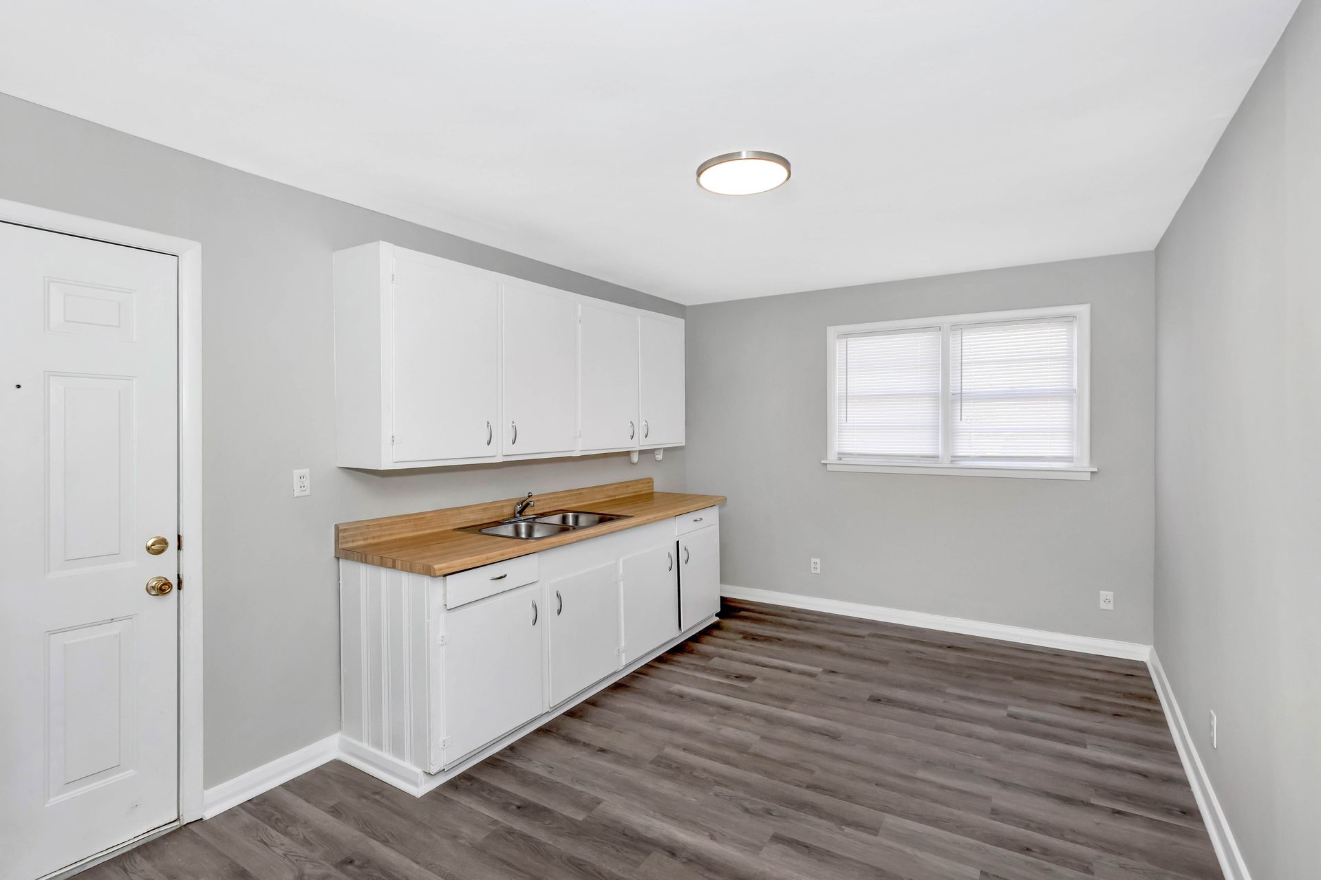 A kitchen with white cabinets , a sink , and a window.