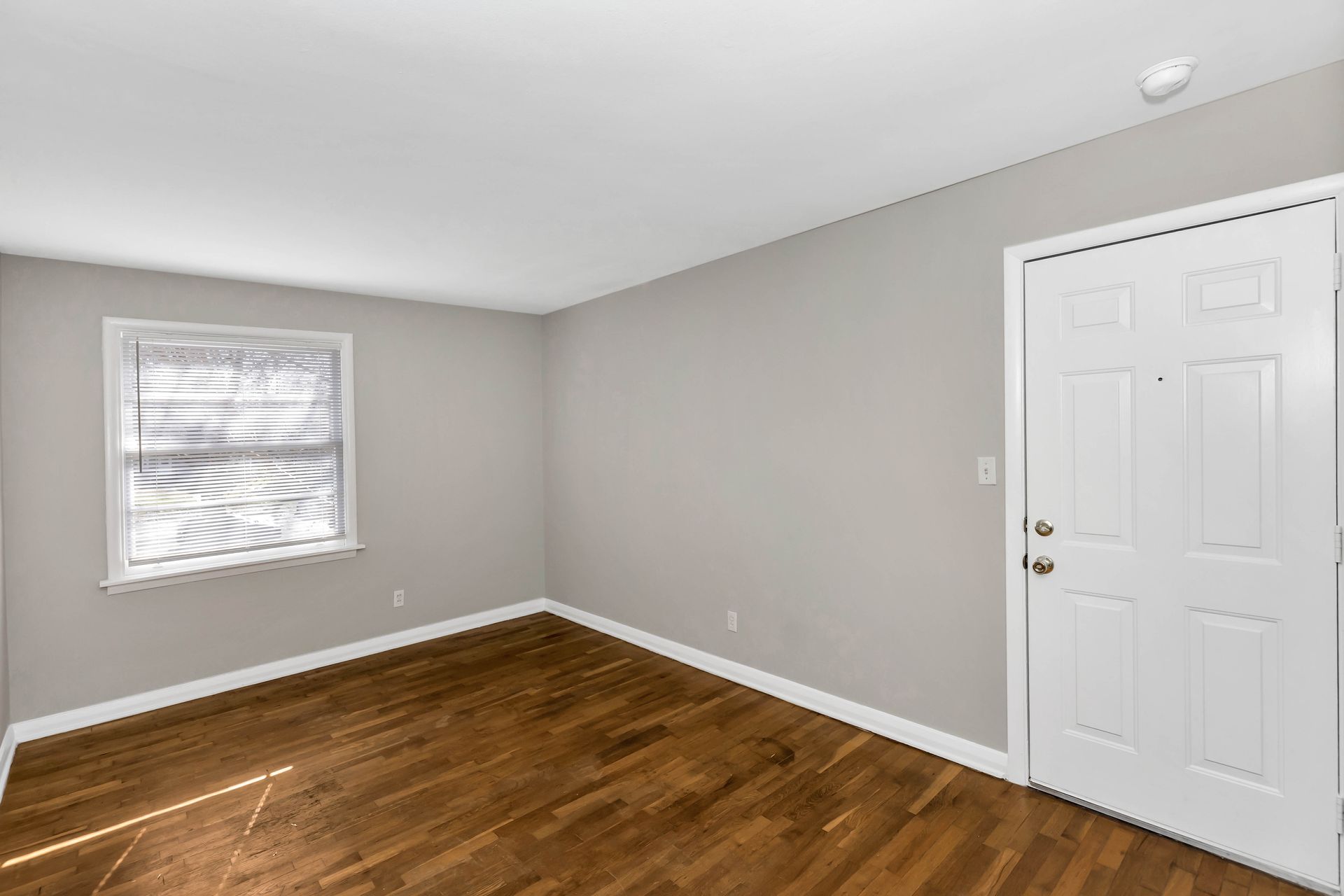 An empty room with hardwood floors and a window.