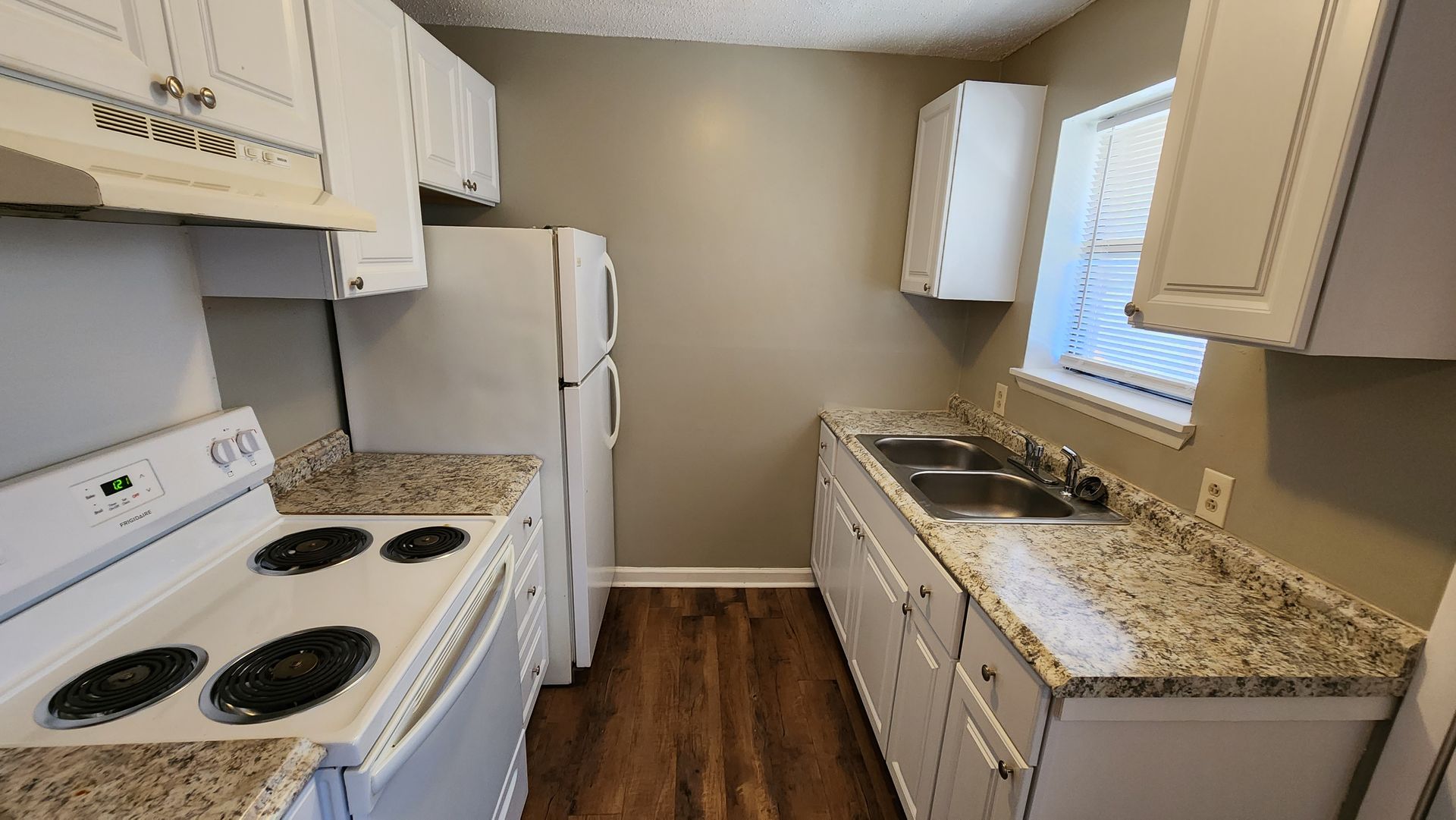 A kitchen with a stove , refrigerator , sink and cabinets.