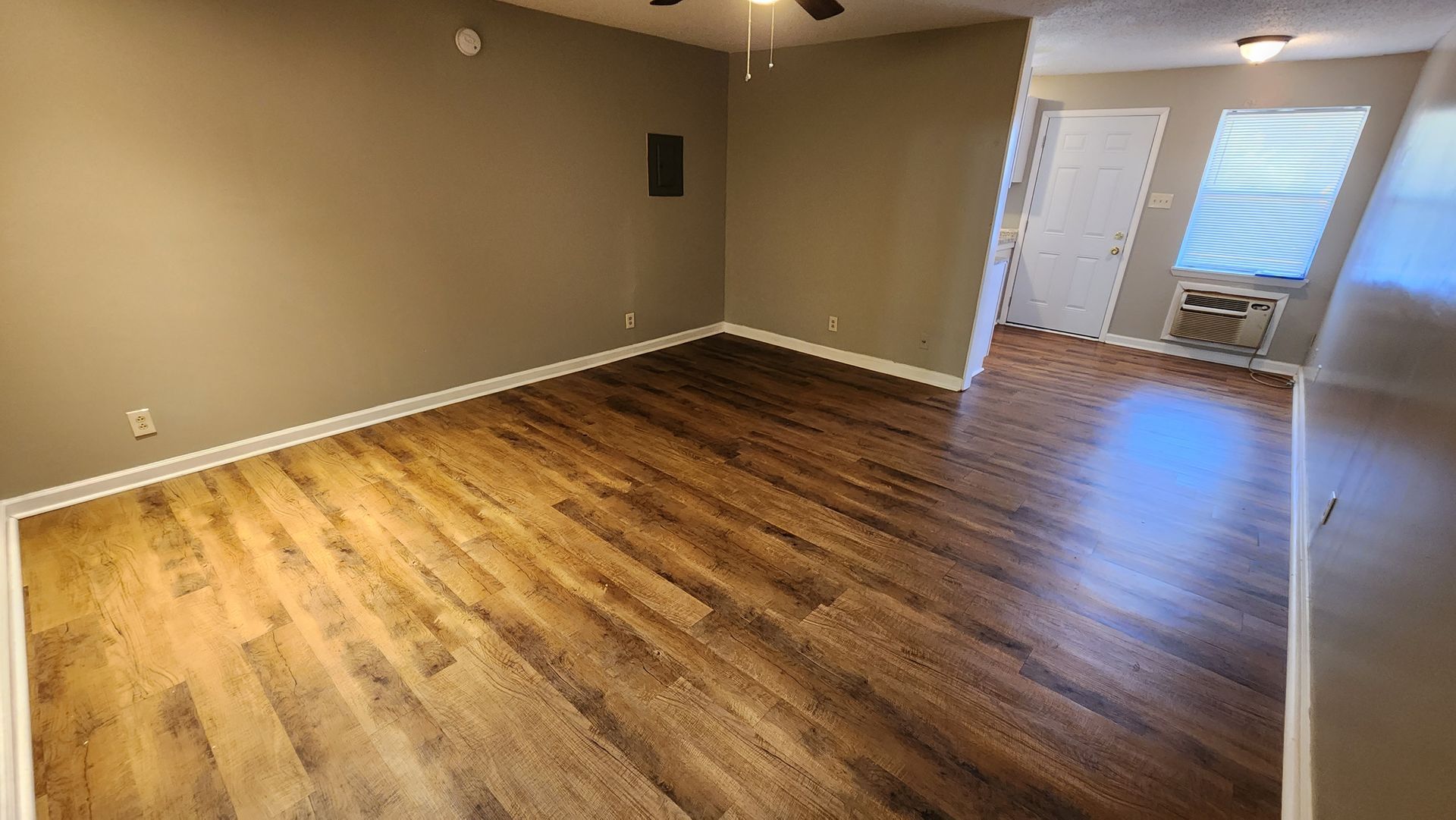 An empty living room with hardwood floors and a ceiling fan.