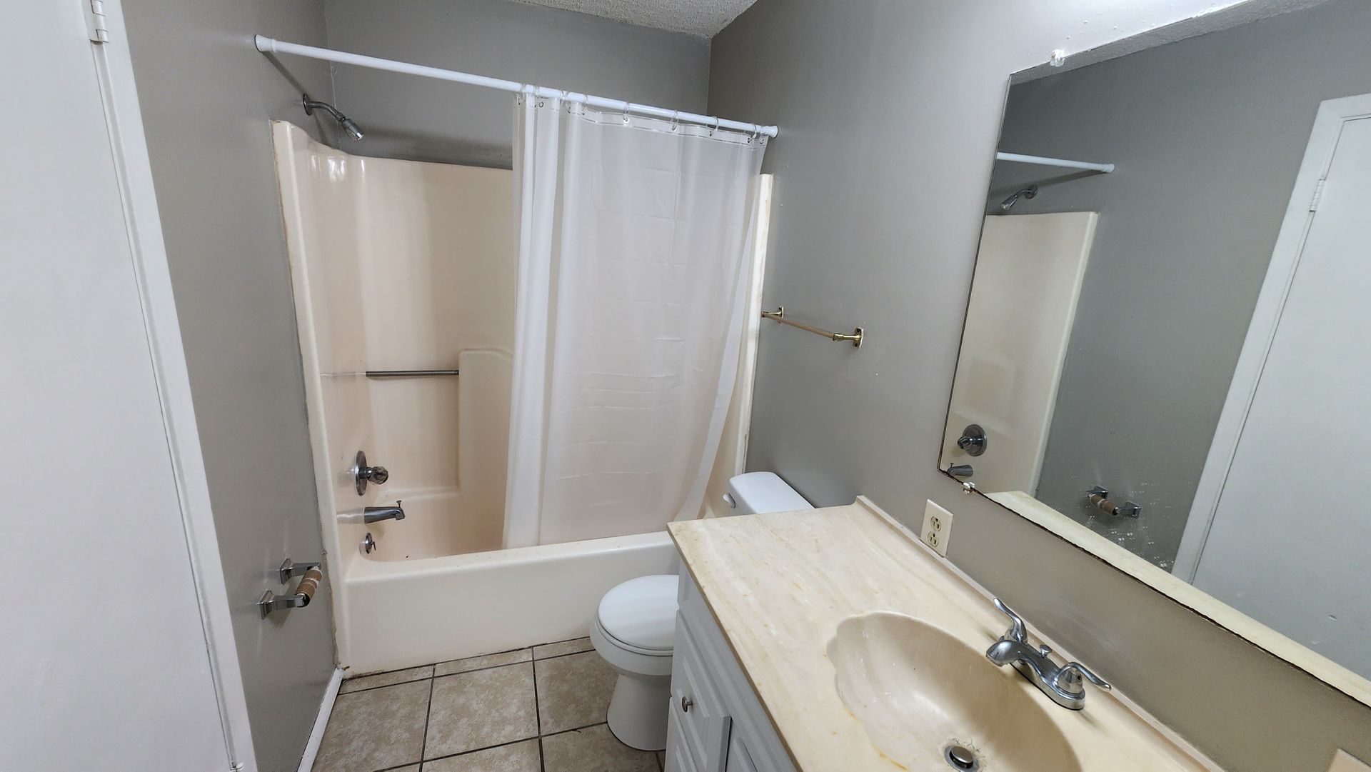 A bathroom with a sink , toilet , shower and mirror.