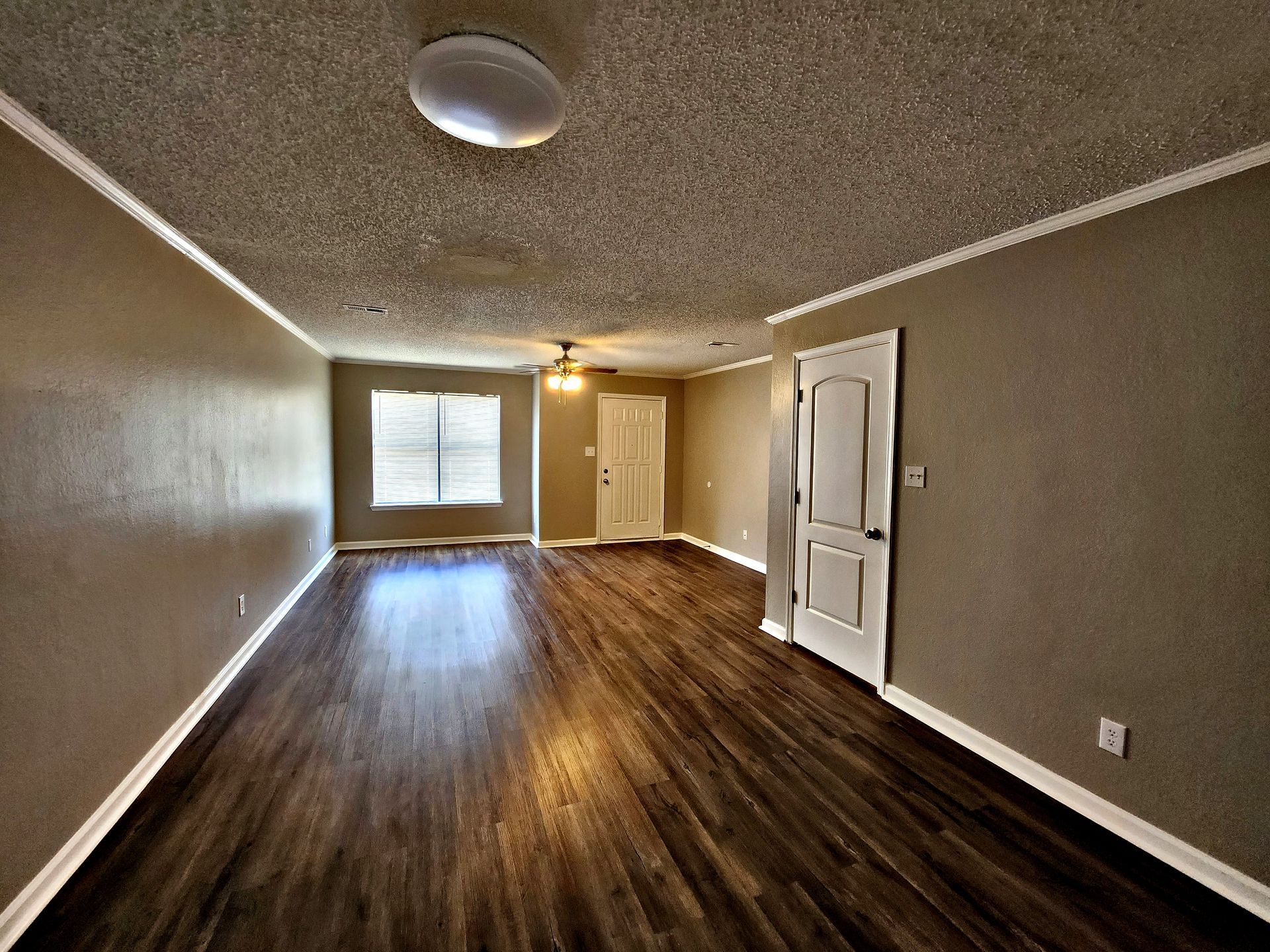 An empty living room with hardwood floors and a ceiling fan.