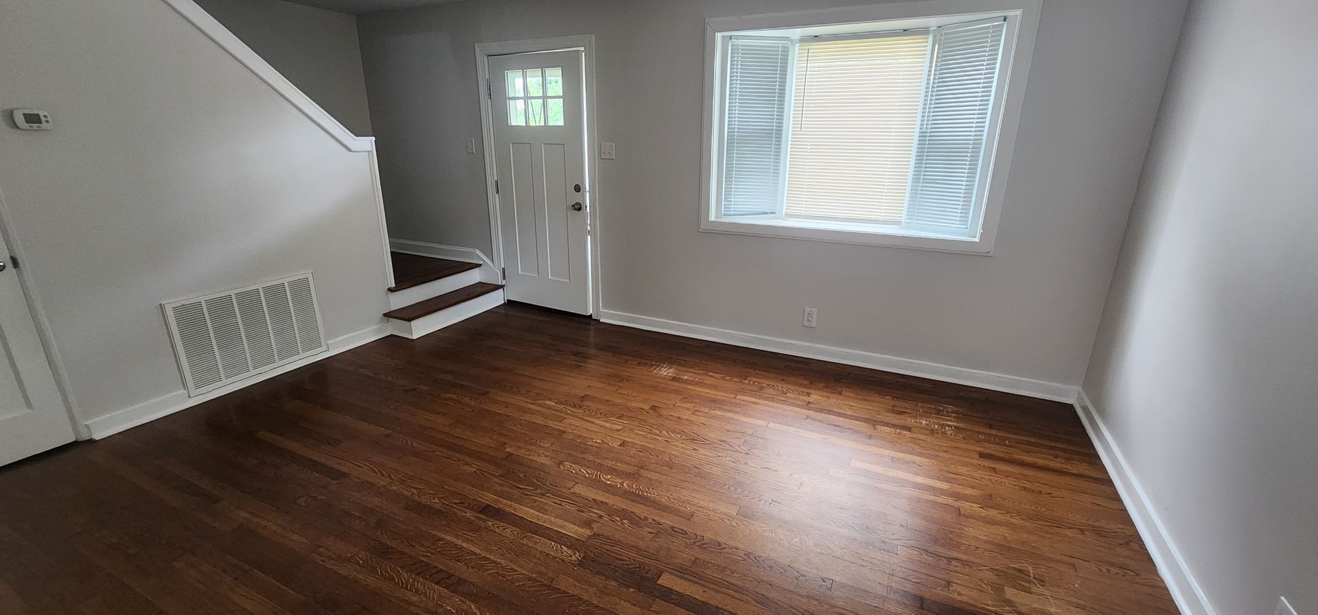 An empty living room with hardwood floors and a window.