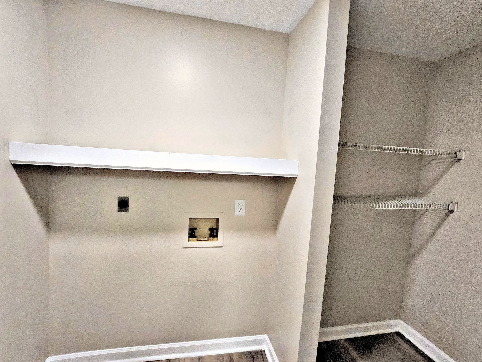 A laundry room with a shelf and clothes racks.
