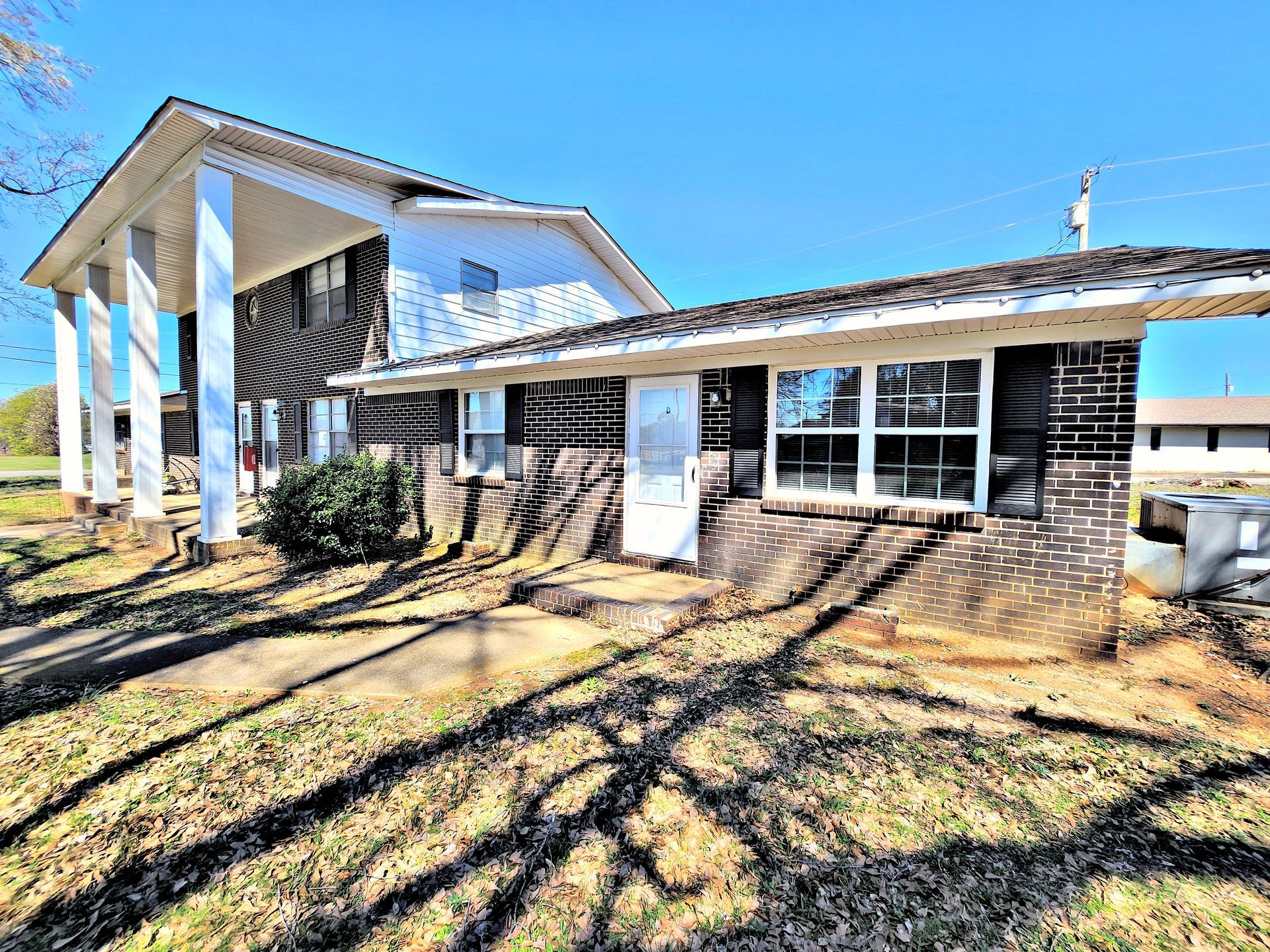 A large house with a large porch and a lot of windows on a sunny day.