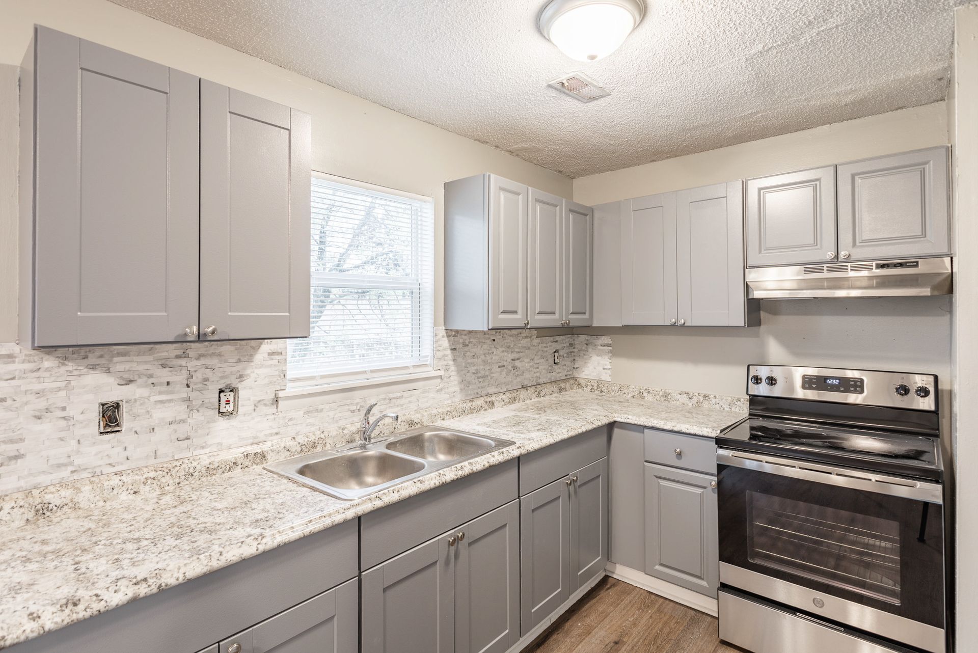 A kitchen with gray cabinets and granite counter tops