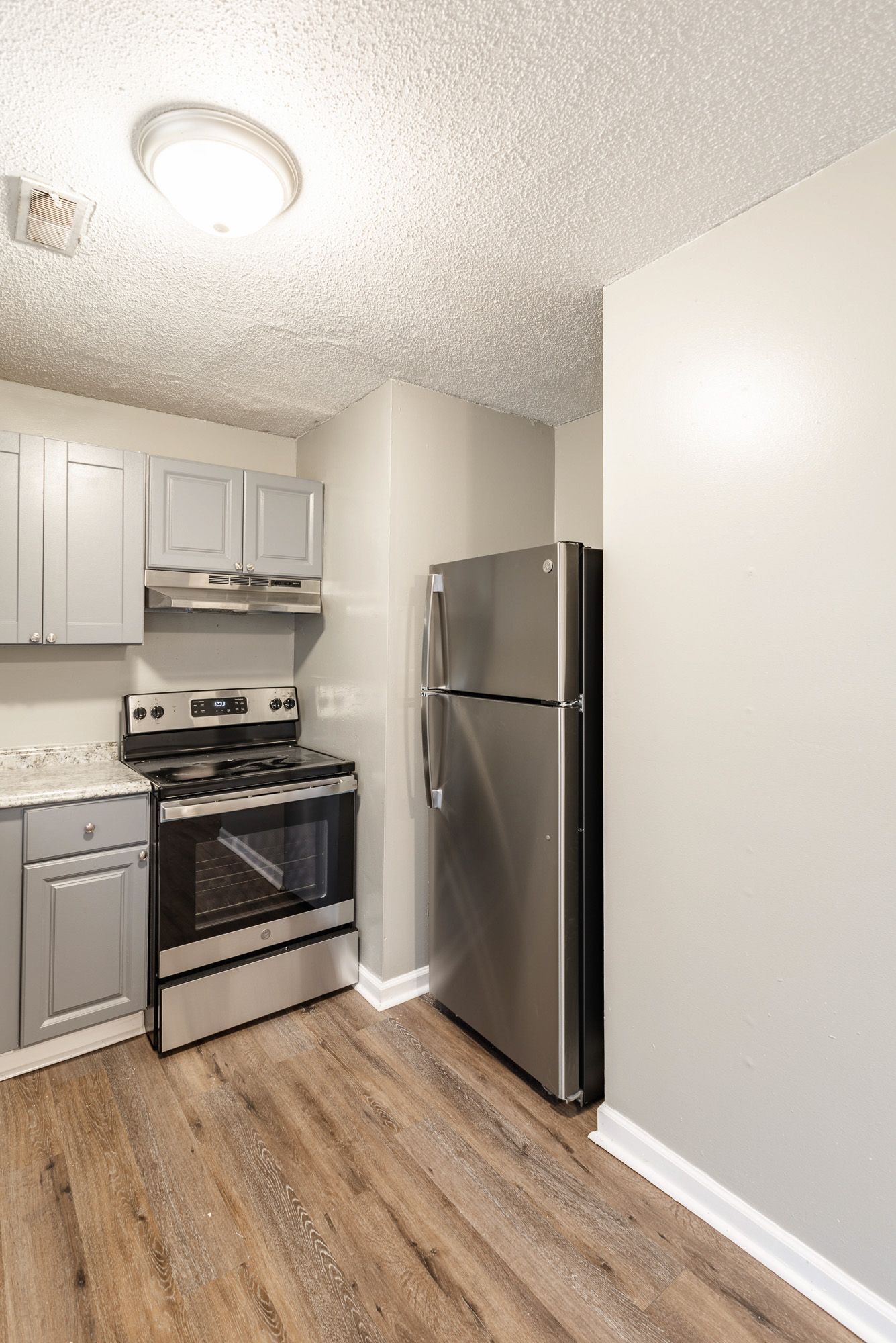A kitchen with a stove , refrigerator , and cabinets.