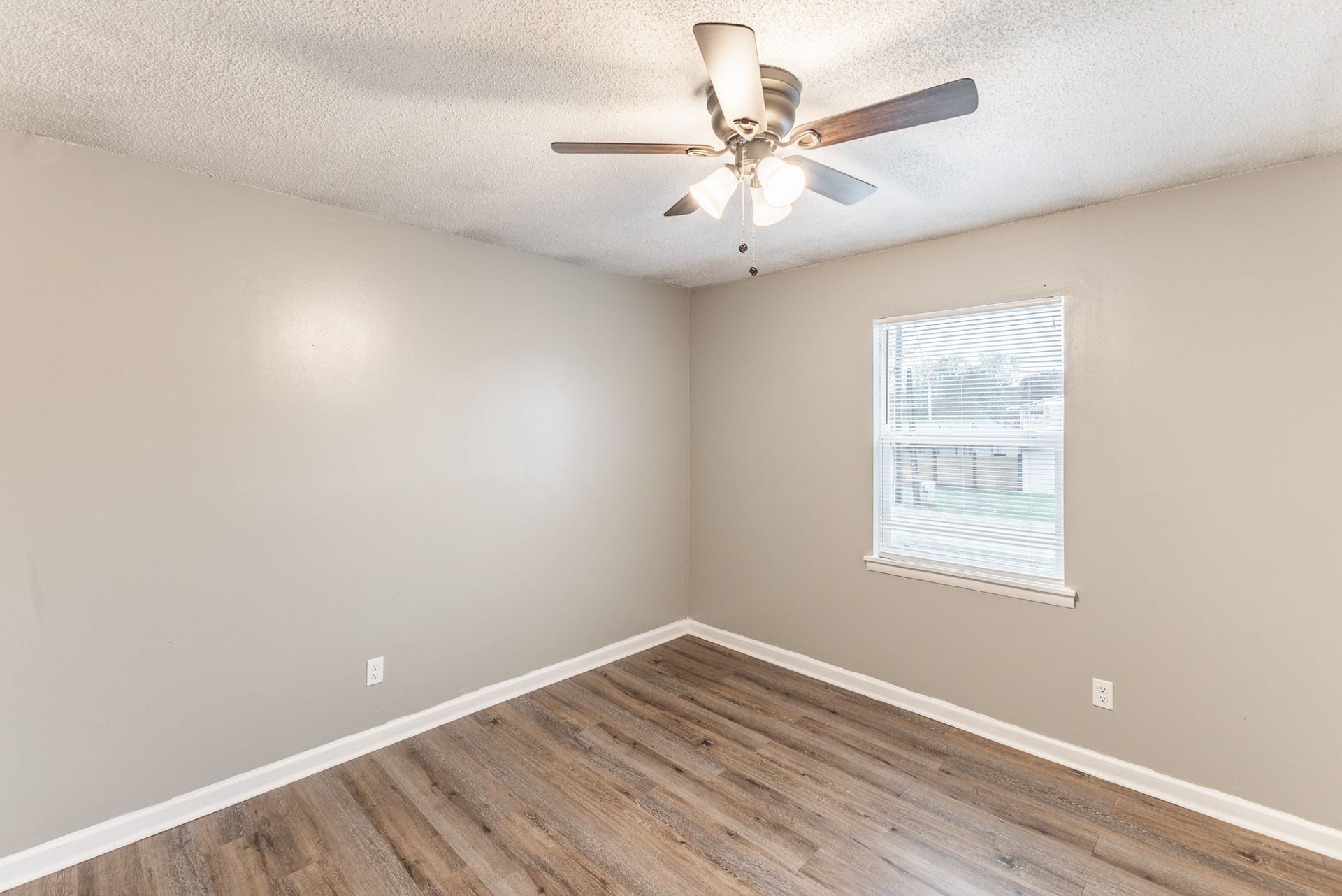 An empty room with a ceiling fan and a window.