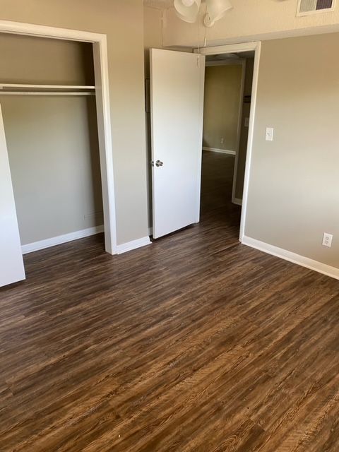 An empty room with hardwood floors and a closet.