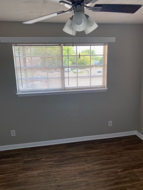 An empty room with a ceiling fan and a window.