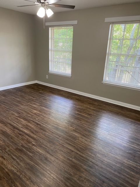 An empty living room with hardwood floors and a ceiling fan.