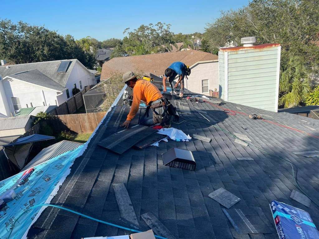 Two men are working on a roof of a house.