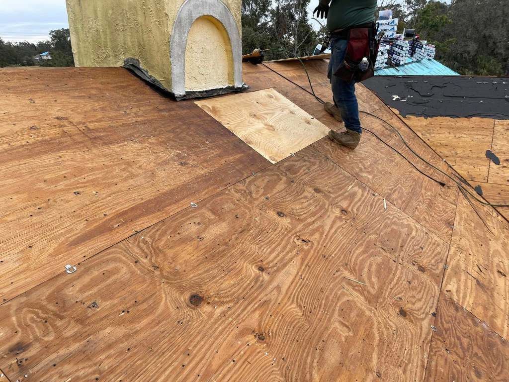 A man is standing on top of a wooden roof.