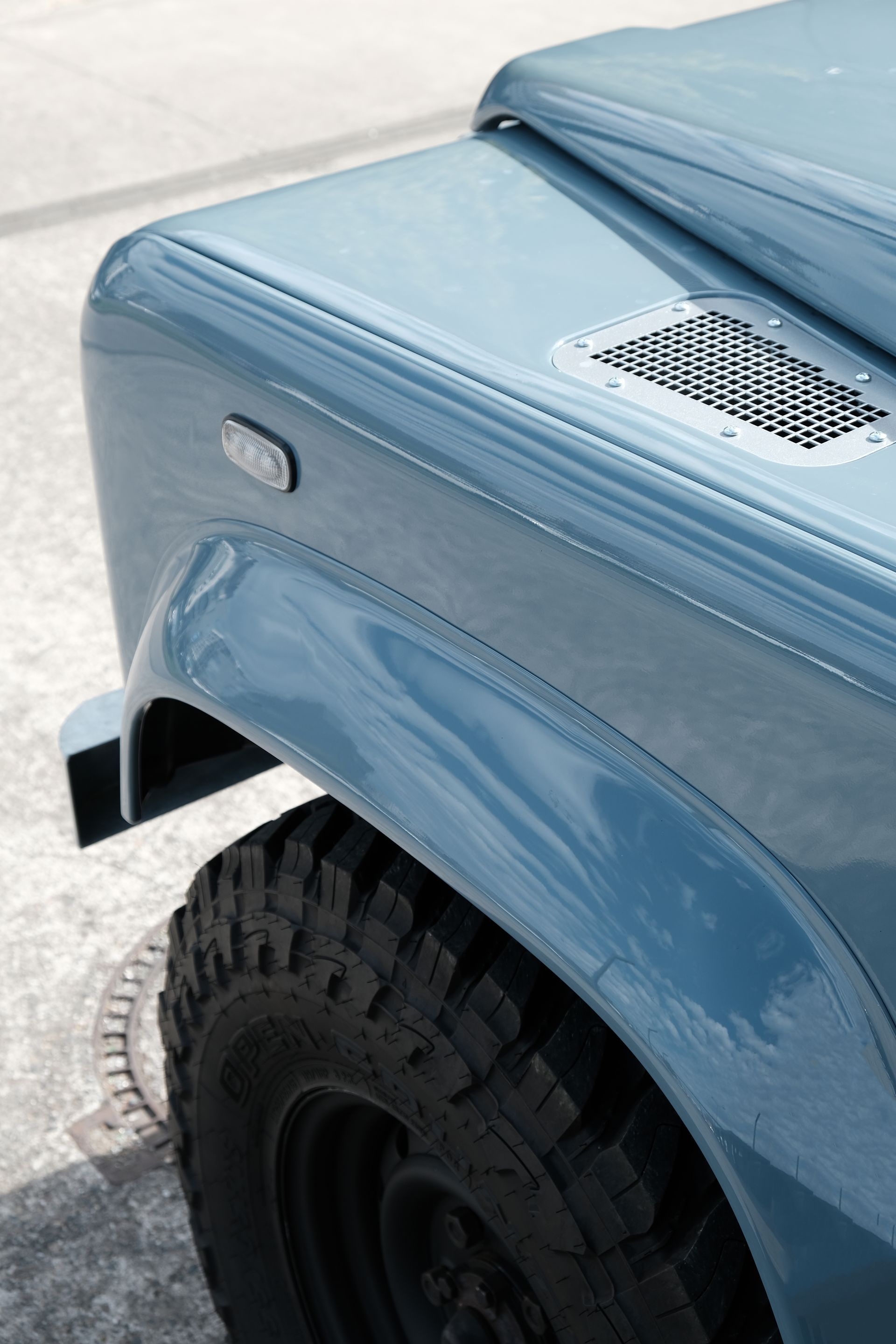 Land Rover Defender bleue, montrant l'aile avant et le pneu.
