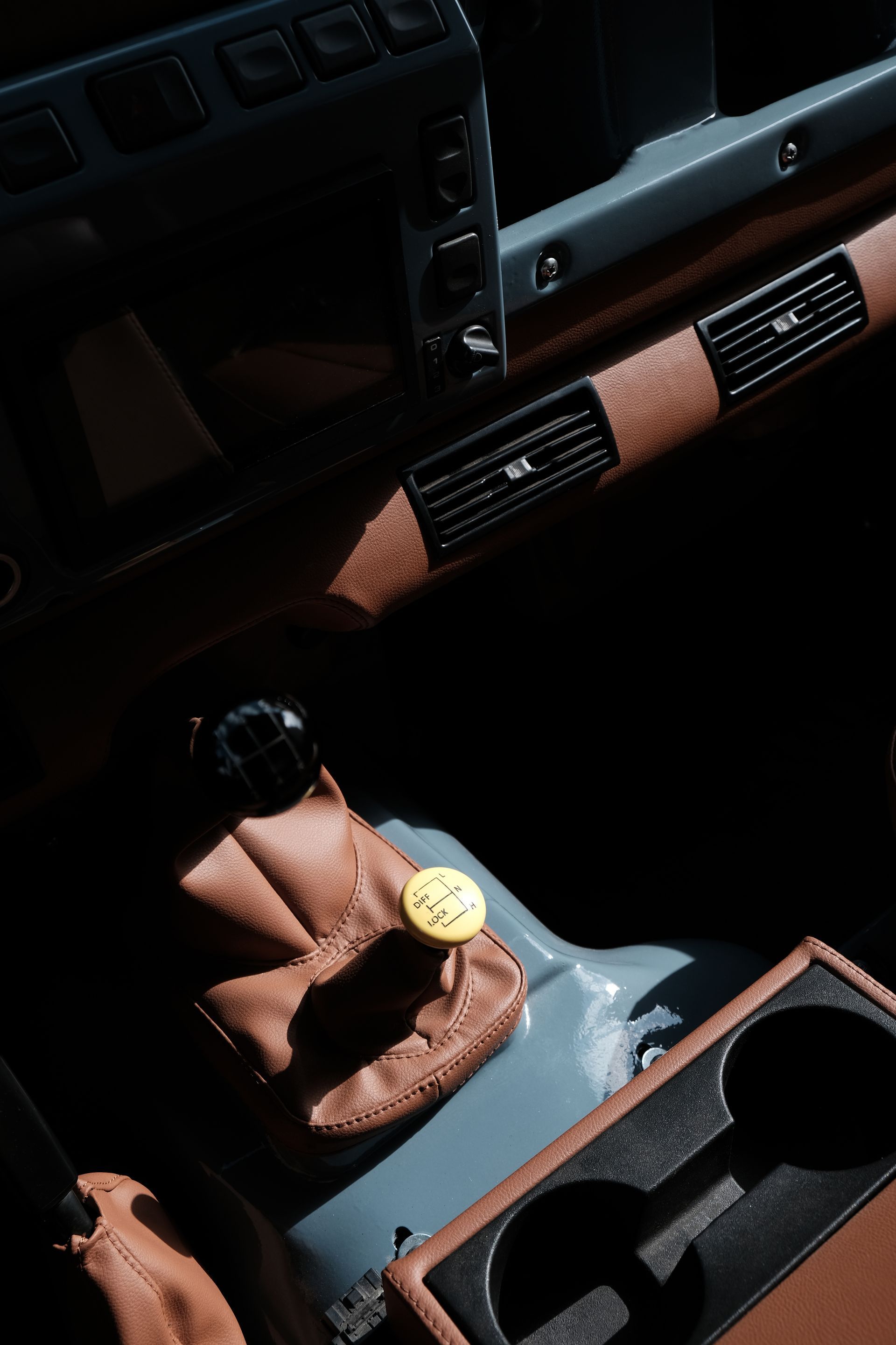 Intérieur d'une voiture avec des finitions en cuir marron et un pommeau de levier de vitesse jaune.