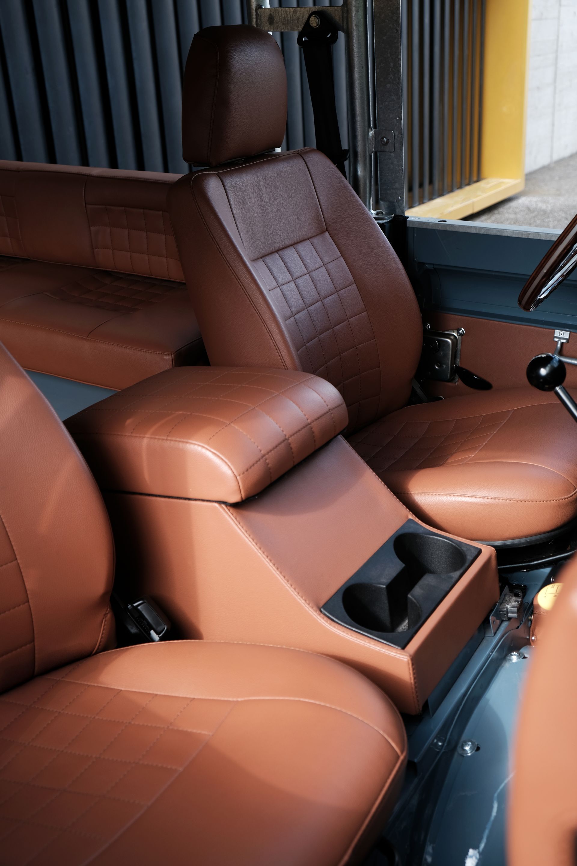 Sièges auto en cuir marron avec console centrale et porte-gobelets.