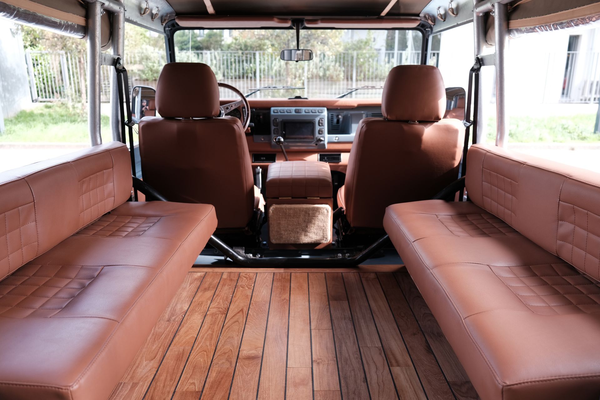 Intérieur d'un véhicule avec sièges en cuir marron et plancher en bois.